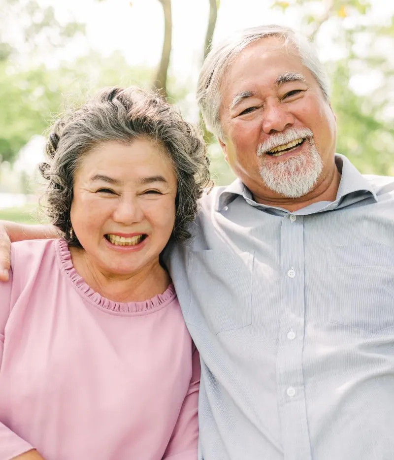 An older couple laughing together on a park bench